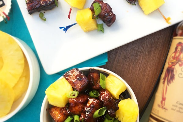 Cubed Slab Bacon Bites Appetizer coated with a Brown Sugar Rum Glaze served with pineapple on toothpicks.